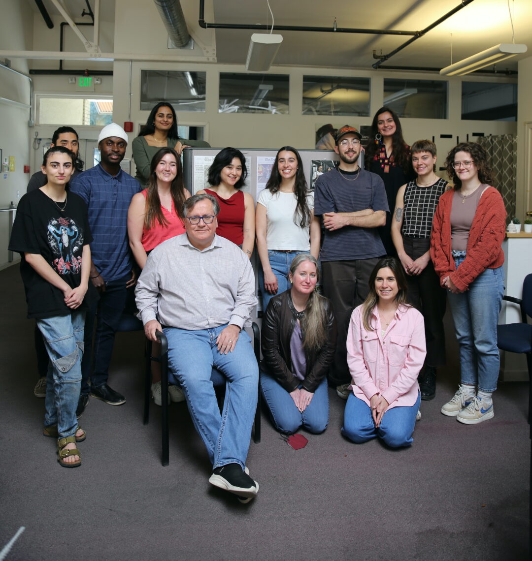Students are gathered around a professor, David Barstow, who is seated in a chair. All are looking at the camera.